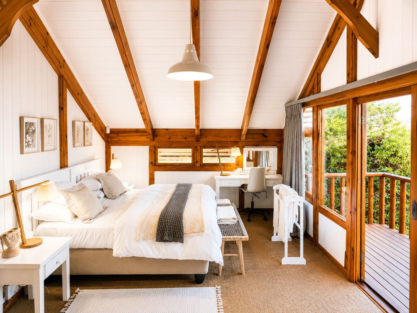Main bedroom with king bed, vaulted pine ceiling and glass doors to a balcony