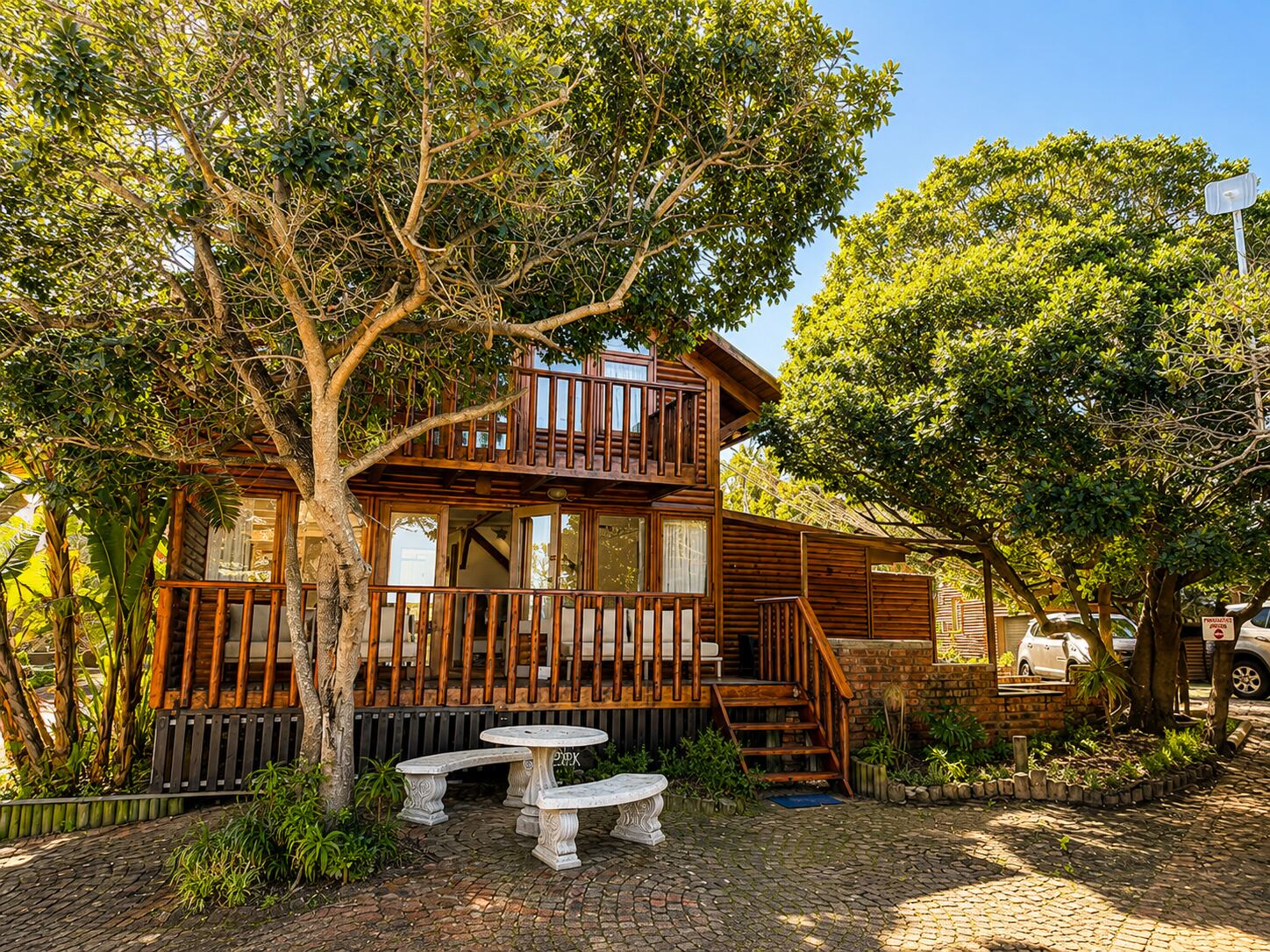Bos Bok lodge exterior with its wooden deck under a large tree